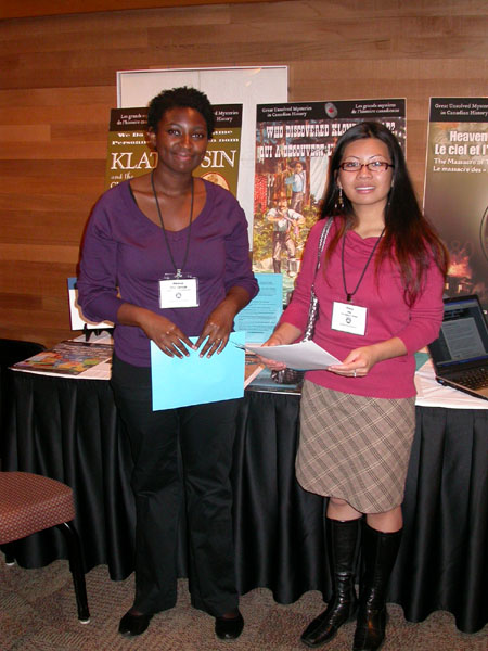 Meleisa Ono-George (left), a research assistant for the Mysteries Project, with a visitor at the display