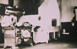 Woman by woodstove in typical Doukhobor communal home